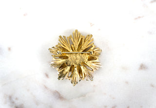 Starburst Brooch Pin. Designer: Boucher Period: 1950s Dimensions: 2” Material: 18k gold plating, faux pearl Condition: Excellent  Boucher created an array of starburst-themed brooches, as they were a popular addition to a woman’s wardrobe at the time. This distinctly more elevated version features a pearl at the center. Numbered. Available at Fonfrege.com