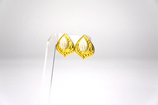 Designer: Yves Saint Laurent  Period: 1980s  Material: gold plated metal, resin shell motif  Measurements: 1”  From Saint Laurent’s Moorish design period comes these stunningly exotic earrings with embossed organic motif surrounding white shells. Clip on. Marked “YSL.” Available at fonfrege.com