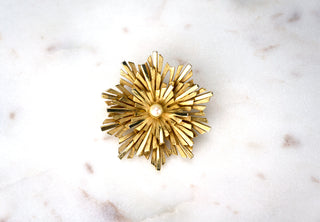 Starburst Brooch Pin. Designer: Boucher Period: 1950s Dimensions: 2” Material: 18k gold plating, faux pearl Condition: Excellent  Boucher created an array of starburst-themed brooches, as they were a popular addition to a woman’s wardrobe at the time. This distinctly more elevated version features a pearl at the center. Numbered. Available at Fonfrege.com